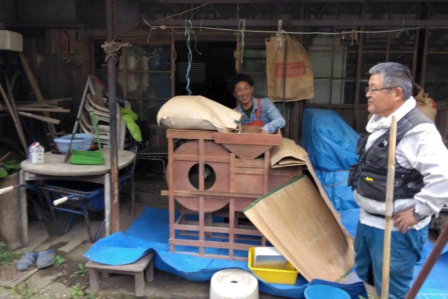 【唐箕（とうみ）を使って、収穫した米のゴミを除去するゆうきさん】